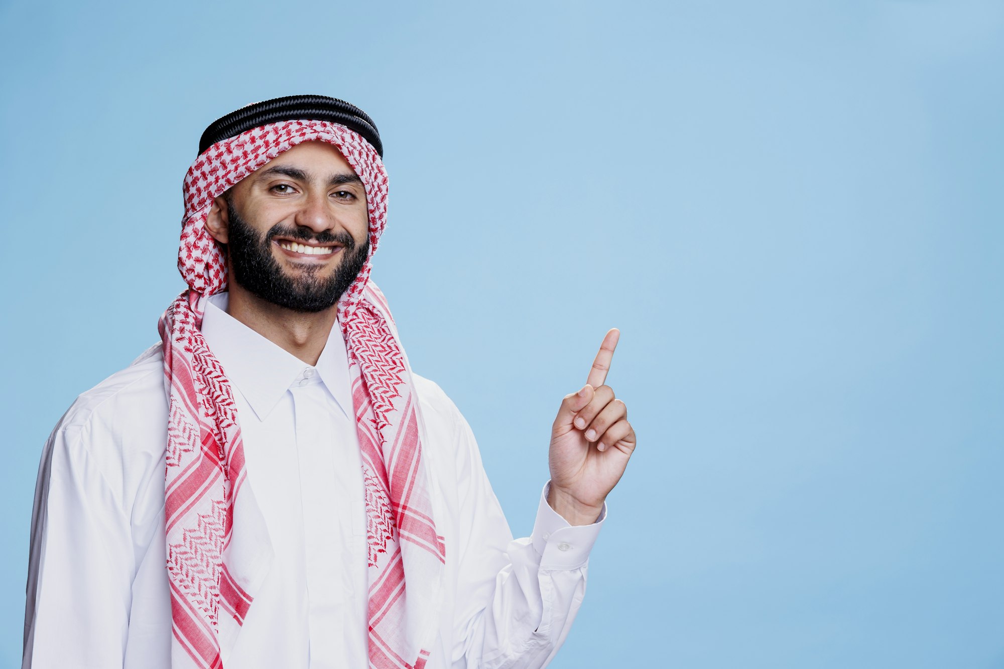Cheerful muslim man pointing upwards
