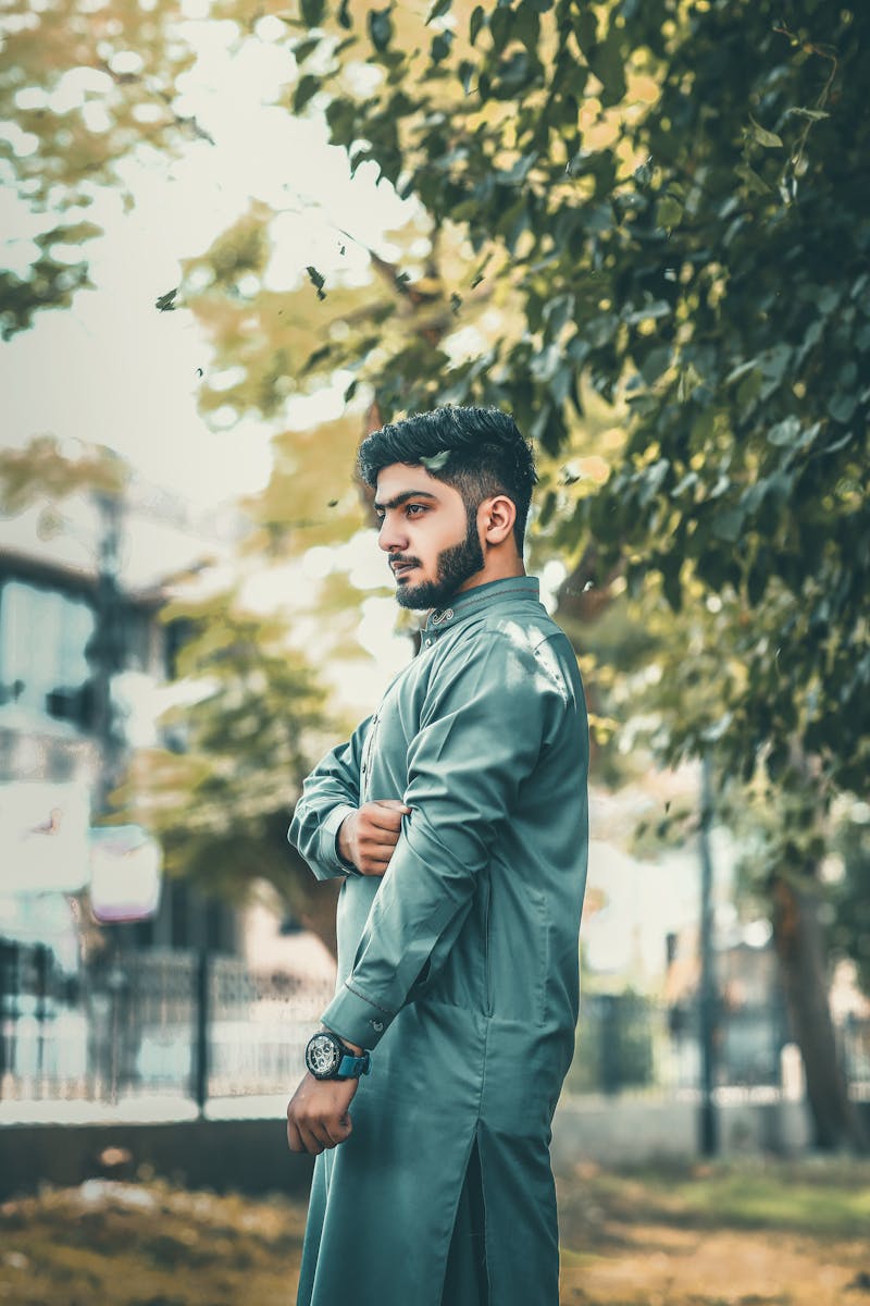 A young man in traditional wear posing in a park setting in Lahore.